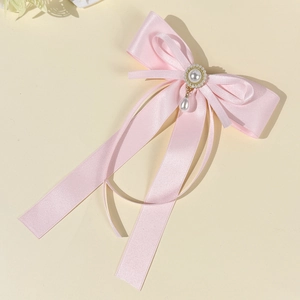 Detail der rosa Seidenschleife Haarspange mit Perlenanhänger und goldfarbenem Akzent