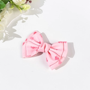 Detail showing layers of light pink satin bow hair clip with red heart patterns