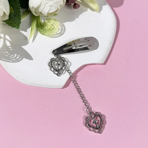 Pince à cheveux en métal argenté avec pendentif coeur et chaîne sur plateau