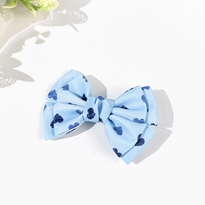 Close-up of light blue ribbon hair bow with dark blue heart pattern and twill texture