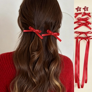 Macro details of red ribbon bow hair clips set with star charms and long streamers