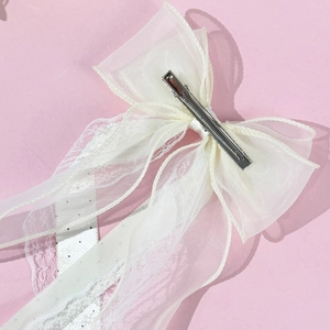 Détail d'une pince à cheveux avec nœud en dentelle et organza crème avec clip argenté