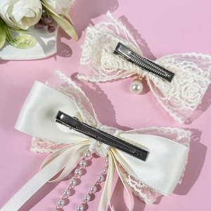 Pince à cheveux nœud en dentelle blanche avec pampille de perles sur fond rose
