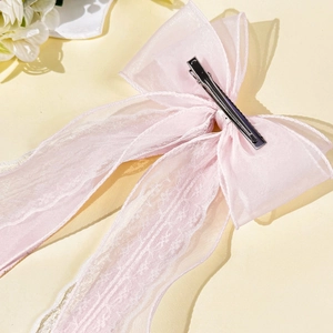 Détail de l'arrière d'un nœud à cheveux en dentelle rose avec ruban organza et pince métal