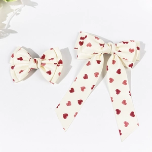 Detail of cream hair bow set with red heart patterns and long ribbon textures
