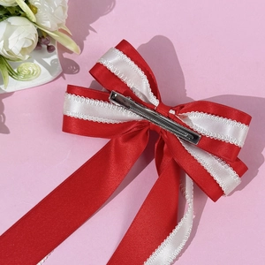 Elegant red satin bow hair clip with lace edges and long ribbons on pink background