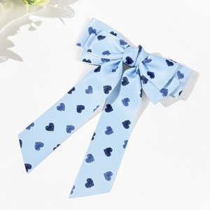 Light blue bow hair clip with dark blue heart patterns and long ribbon streamers