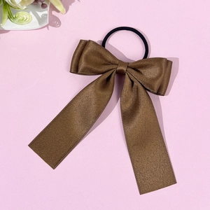 Détail du chouchou en satin marron café avec un nœud papillon et de longs rubans élégants