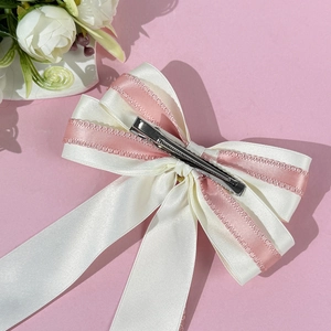 Detail of multi-layer pink and white ribbon bow hair clip with silver metal duckbill clip