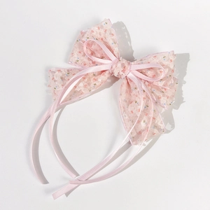Dettaglio del cerchietto rosa con pizzo floreale, doppio fiocco e nastri lunghi