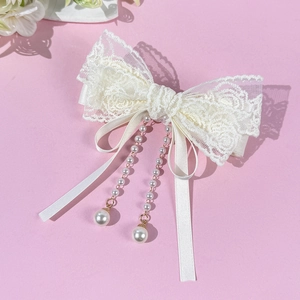Détails de la barrette nœud en dentelle crème avec pompons en perles et rubans