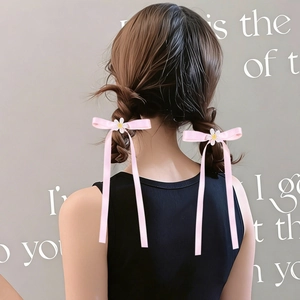 Detail of pink satin bow hair clips with white daisy flower accents on model