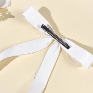 Detail view of the silver metal alligator clip and white satin texture on ribbon hairbow