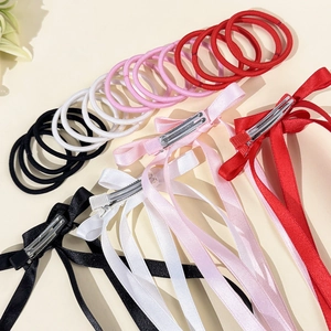 Detail of four-color ribbon bow hair clips with elastic ties and smooth satin texture