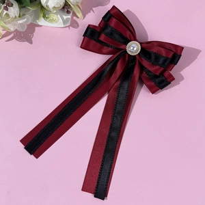 Detail of burgundy satin ribbon and black lace bow with elegant pearl center embellishment
