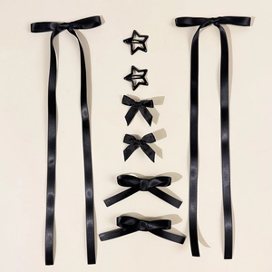 Flat lay of black ribbon bows and star-shaped hair clips on a beige background