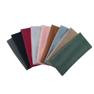 Flat lay of nine colorful knitted headbands showing ribbed texture and elastic fabric