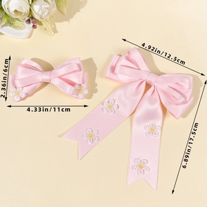 Détail de barrettes nœuds en satin rose avec broderie marguerite et dimensions