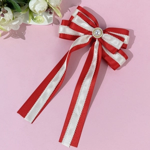 Detailed shot of a red and white bow hairclip with lace edges and a central pearl accent