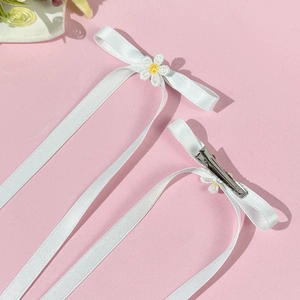Set of two white ribbon bow hair clips with daisy flower embroidery on pink backdrop