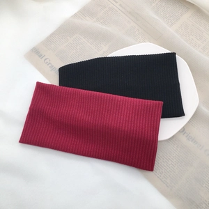 Detail view of elastic ribbed knit headbands in black and burgundy on a white plate