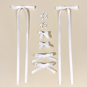 Flat lay of an 8-piece set featuring white satin ribbon bows and star hair clips