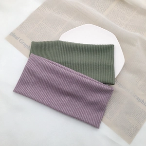 Detailed close-up of ribbed knit headbands in purple and moss green on a white plate