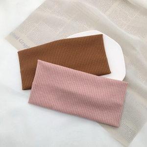 Detail of ribbed knit headbands in dusty pink and caramel brown on a white tray