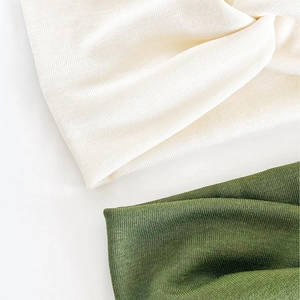 Détail de la texture en maille et du nœud sur des bandeaux crème et vert olive