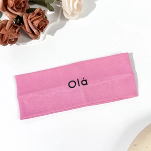 Detailed macro view of pink elastic yoga headband fabric featuring black Olá text print