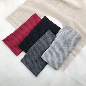 Detail of ribbed knit headbands in dark red, black, and grey on white porcelain display