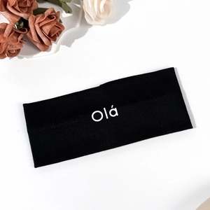 Detail of black elastic yoga headband with Olá printed text and soft knit texture