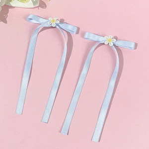 Detail of light blue ribbon bows with white embroidered daisy flowers for hair decoration