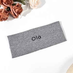 Close-up of grey knitted yoga headband with black Olá letter print and soft texture