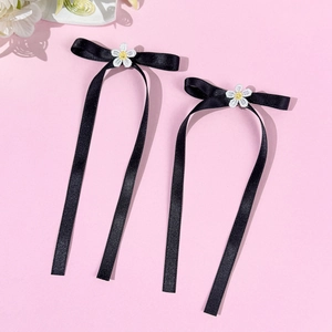Detail of black ribbon bow hair clips with white lace daisy centers and long streamers