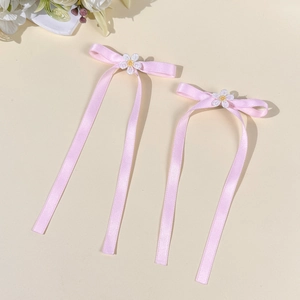 Detailed view of pink satin ribbon hair clips with white daisy flower embroidery and long streamers