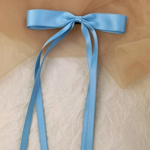Detail shot of light blue satin ribbon bow hair clip with elegant long streamers