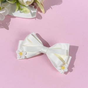 Détail du nœud papillon en satin blanc crème avec broderie de fleurs de marguerite