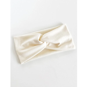 Détail d'un bandeau élastique crème montrant le tissu tricoté et le nœud croisé