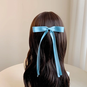 Detail of light blue satin ribbon hair clip with long streamers on wavy hair