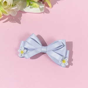 Vue détaillée du nœud en satin bleu clair avec des fleurs de marguerites brodées blanches