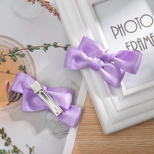 Detail view of purple satin double bow hair clips with metal duckbill clip back