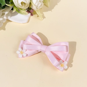 Détail de la barrette à cheveux en satin rose avec broderie de marguerites blanches