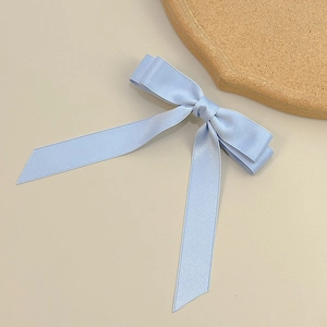Detail of light blue satin double bow hair clip with long elegant flowing ribbons
