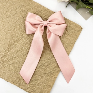 Détail d'un grand nœud papillon en satin rose avec de longs rubans sur papier texturé