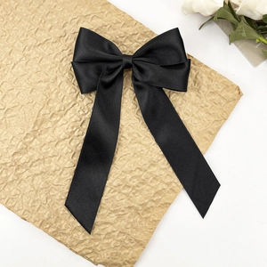 Détail d'un élégant nœud à cheveux en satin noir avec texture soyeuse et pointes en queue