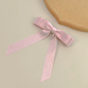 Detail view of the pink satin double-layered bow hair clip with elegant long ribbons