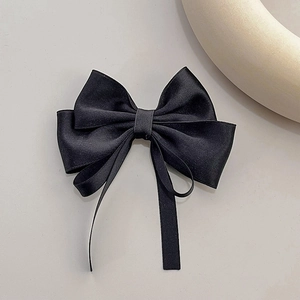 Detail of multi-layer black satin bow hair clip with elegant long ribbon streamers