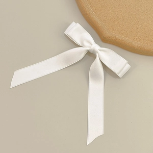 Detailed view of the smooth white satin texture on a double-layered bow hair clip