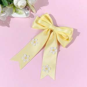 Détail d'une barrette à nœud en satin jaune avec broderies marguerites de style pastoral
